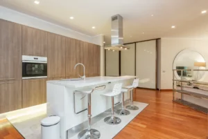 Modern kitchen with a sleek bar stool featuring a wooden seat and metal legs placed by a marble countertop